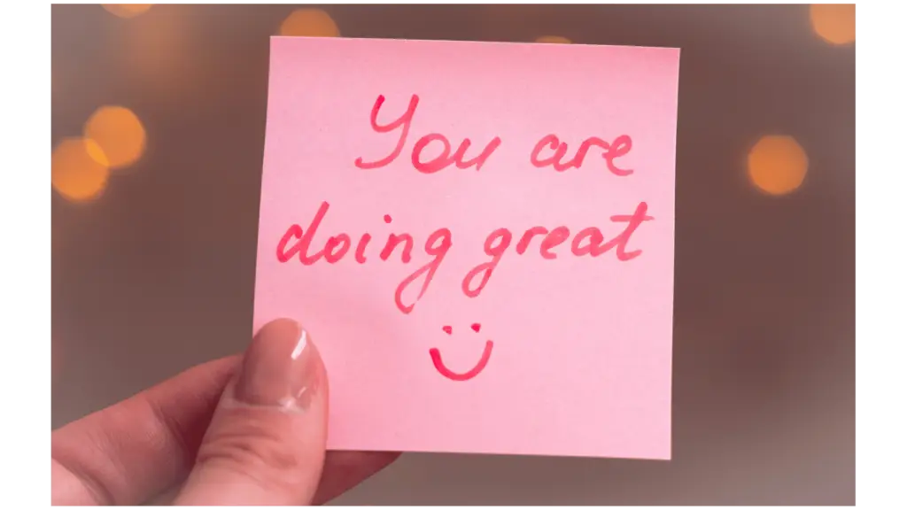 A close-up of a pink sticky note with the handwritten message "You are doing great" and a small smiley face drawn underneath.