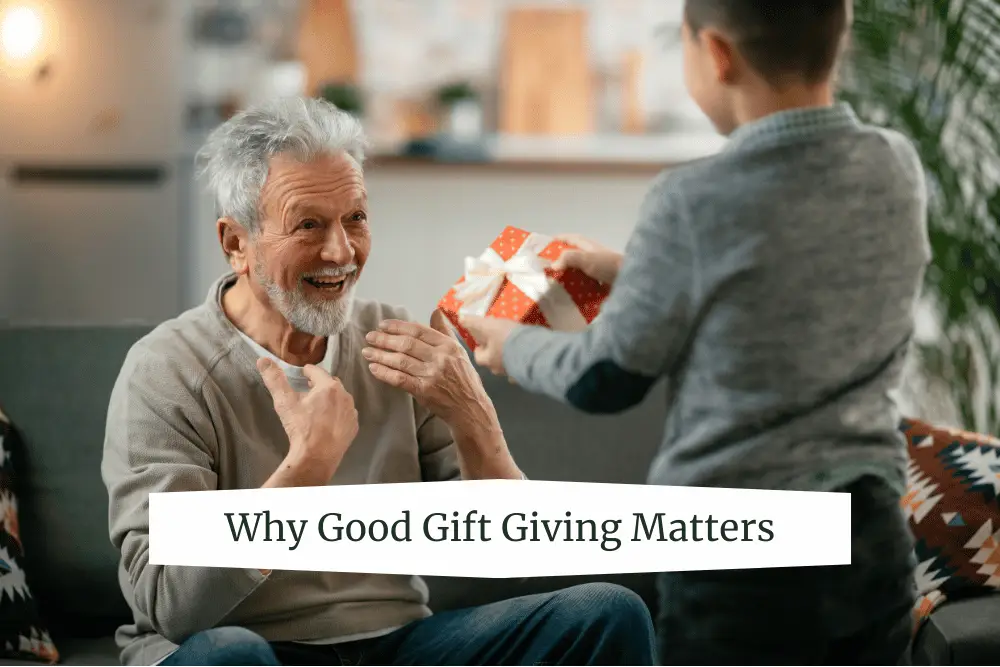 An elderly man smiles with joy as a young child hands him a gift wrapped in red and white paper. The scene captures the happiness of thoughtful gift-giving in a cozy home setting.